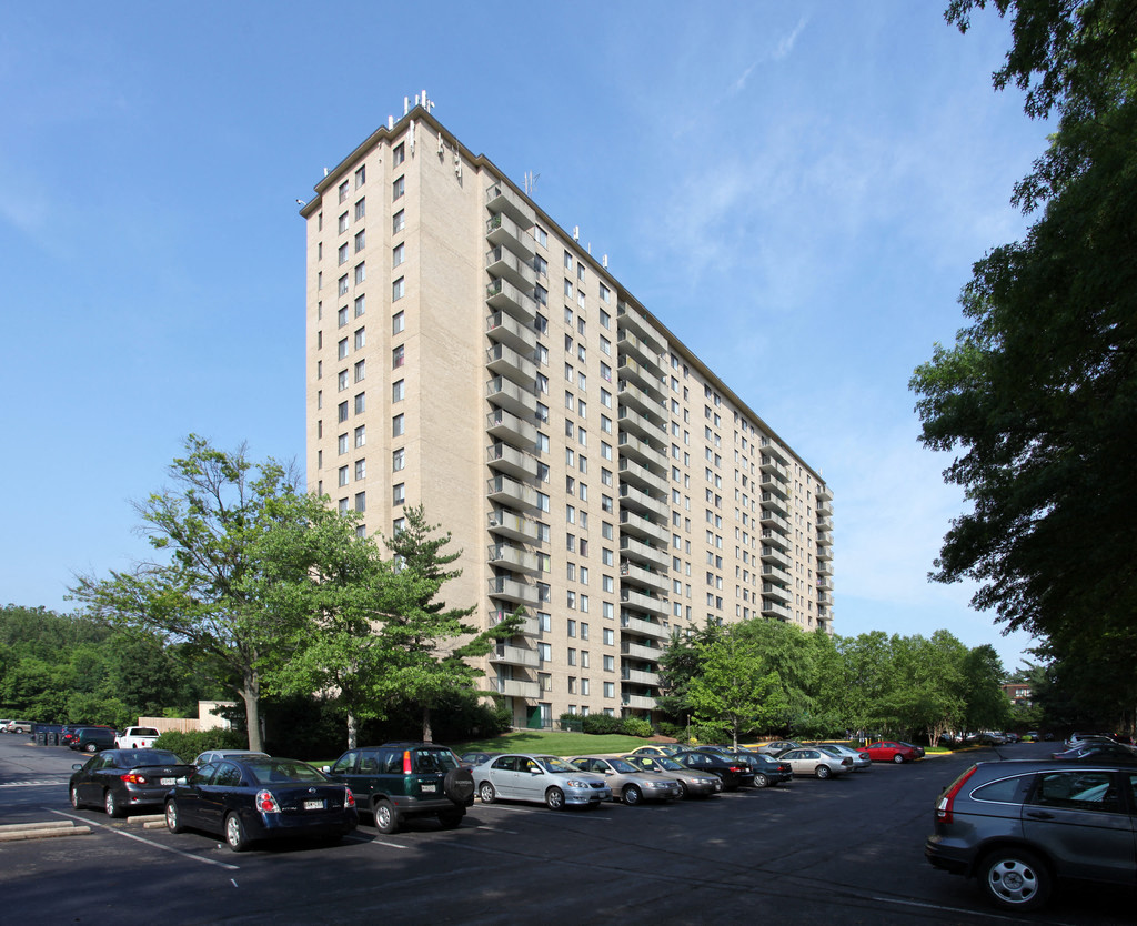 A tall apartment building with a parking lot in front of it.